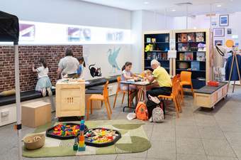 The Learning Space at Tate Liverpool + RIBA North. There are families sitting whilst drawing and doing crafts.