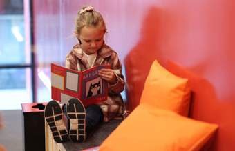 A photograph of a child looking at an activity booklet which has a picture of a cartoon cat on the front cover.