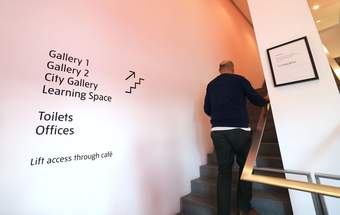 A visitor walking up the stairs at Tate Liverpool + RIBA North