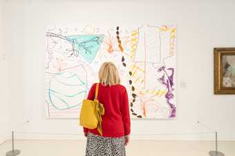 a person looks at an artwork by Rose Wylie with their back to the camera