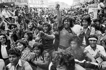 A crowd of people shouting, one person's fist raised