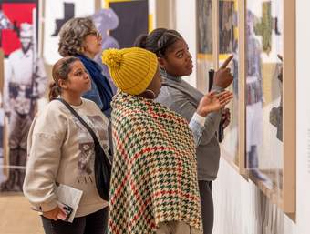 Several teachers look at and discuss artwork on a gallery wall