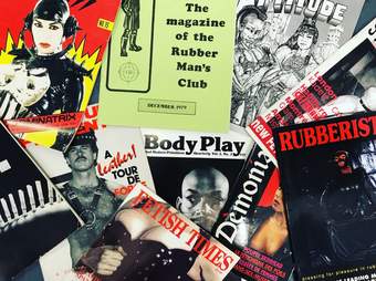 Close up of several vintage magazines and posters with men and women dressed in leather with various titles and slogans alluding to kink