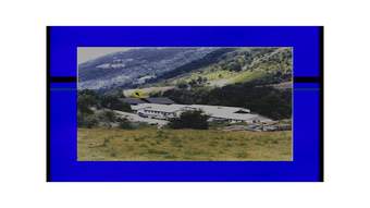 A digital image of a long white building in the mountains with a computer mouse hovering over the picture