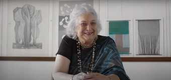 Photograph of Monika Correa sitting at a table looking towards the camera