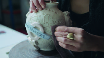 Hands making a pot inspired by the work of Grayson Perry