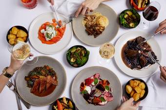 Plates of festive food and glasses of wine on a white tablecloth