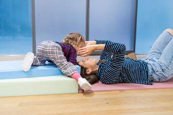 A woman lies on the floor looking up at a child