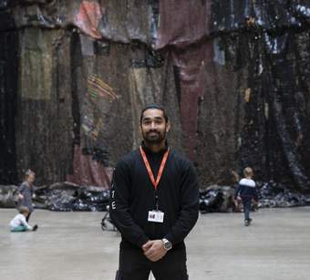 A person smiling wearing black clothes with an orange lanyard