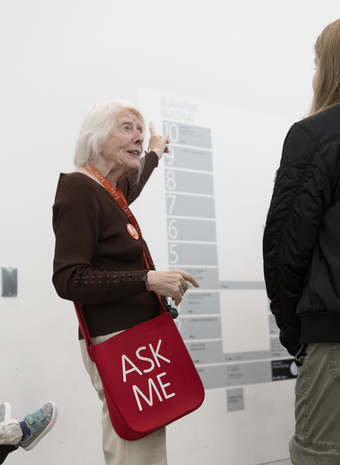 A person wearing a red lanyard pointing at a wall map